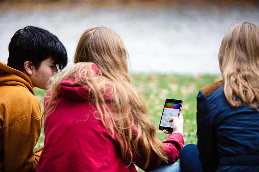 Tre ungdommer ser på mobilskjerm