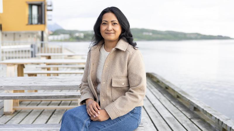 Dame som sitter på kaia